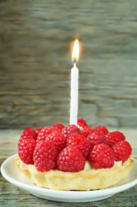 tartlet with raspberry and cream cheese and a candle on a dark wood background. tinting. selective focus