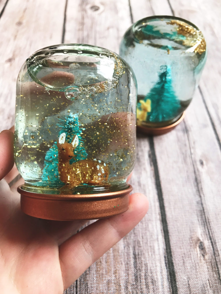 These DIY mini snow globes are perfect for when you need multiple affordable gifts to handout or accompany a Christmas gift basket. Easily made from baby food jars, glitter, and adorable mini Christmas figures. 